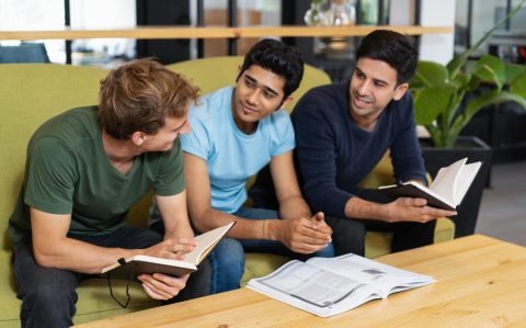 Three,Fellow,Students,Talking,And,Studying,Together.,Young,Men,Sitting